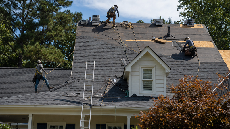 Roof replacement crew installing architectural shingles on a suburban Atlanta home